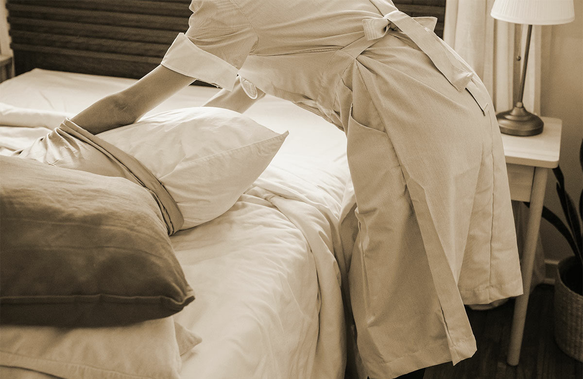 Femme de chambre faisant le lit d'une chambre d'hôtel
