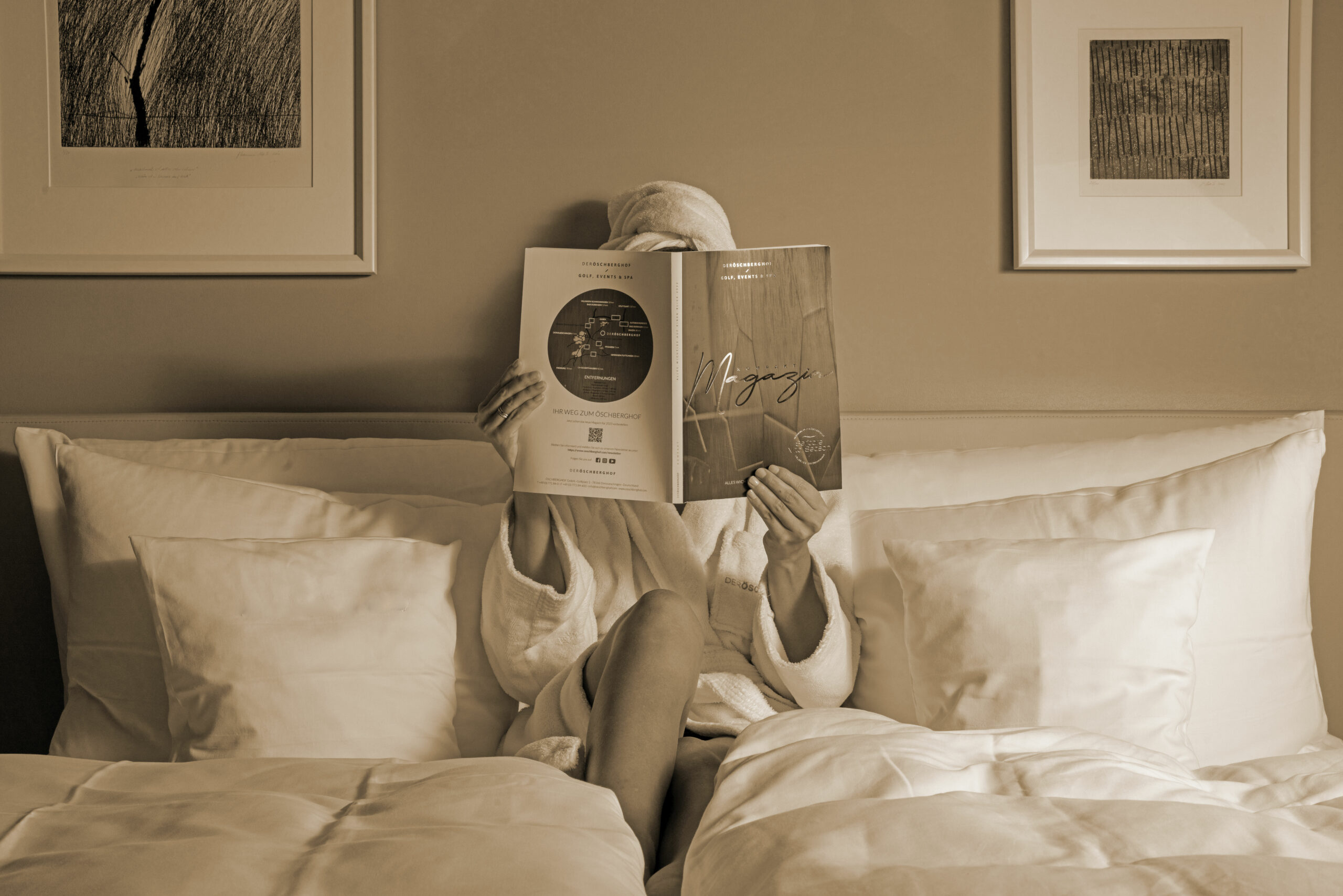 Client en peignoir lisant dans un lit d'hôtel aux draps blancs impeccables