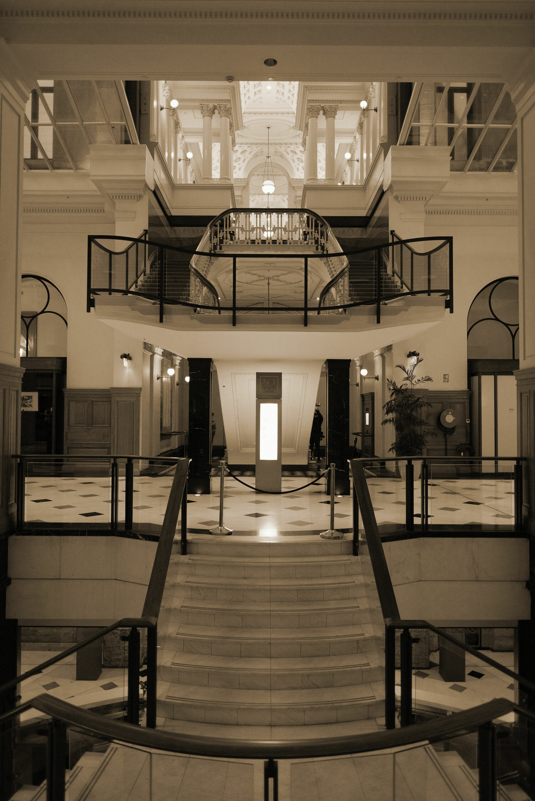 Hall d'hôtel palace à double hauteur avec escalier monumental symétrique, lustres cristal et galeries à balustrades, entretien grands espaces housekeeping