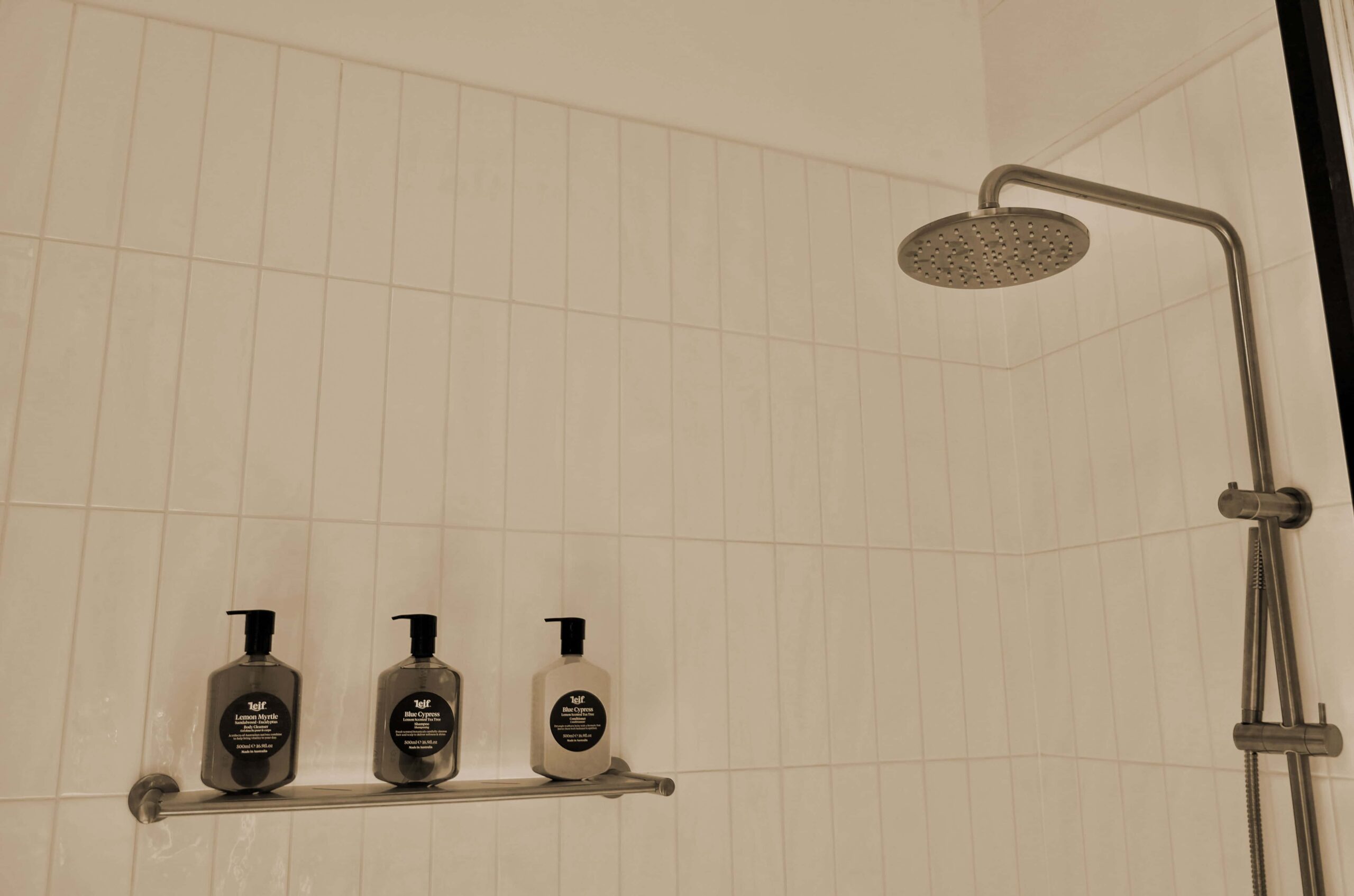 Douche italienne hôtel haut de gamme avec trois flacons d'amenities premium alignés, reflet des standards housekeeping et hygiène du Groupe St Ho